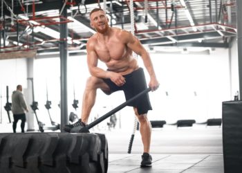 Atleta de crossfit praticando exercício com marreta e pneu - a glutamina favorece o anabolismo muscular e reduz o catabolismo