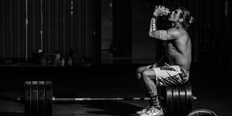 Homem tomendo suplemento l-carnitina na academia