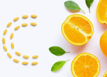 Comprimidos laranjas de vitamina c, formando um c, e metade uma laranja