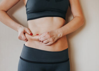 mulher apertando barriga, percentual de gordura