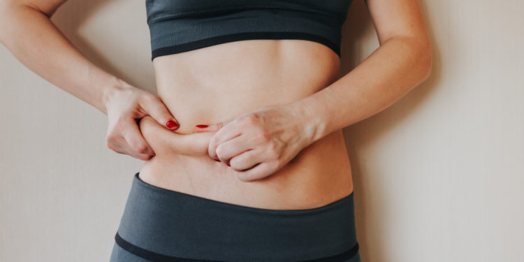 mulher apertando barriga, percentual de gordura