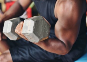 homem levantando halteres, mostrando as fibras musculares