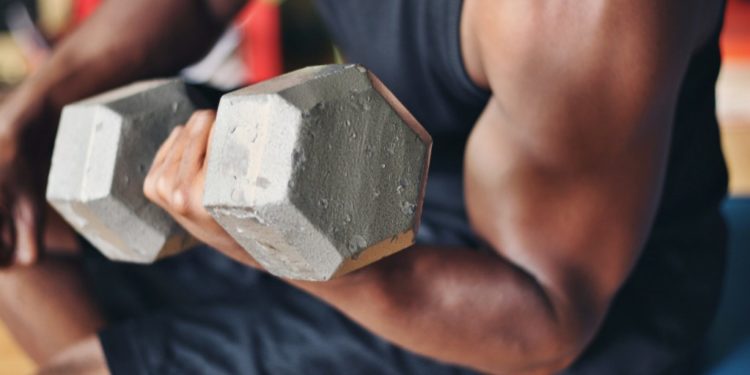 homem levantando halteres, mostrando as fibras musculares
